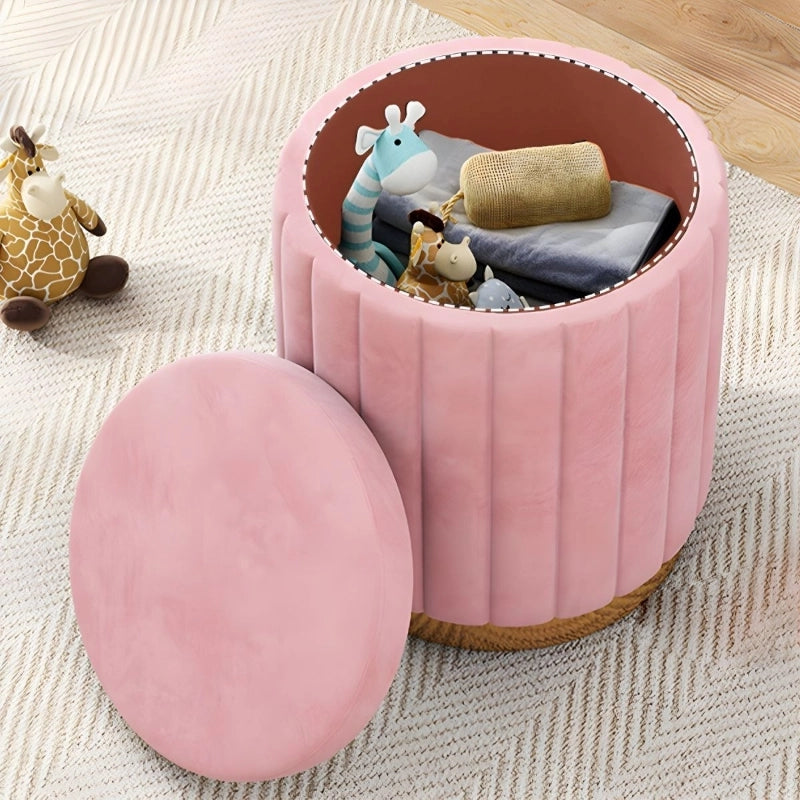 The Aria pouffe ottoman blends visual elegance with daily utility. Its cylindrical velvet form, detailed with vertical pleats, sits atop a gold-tone plinth base—subtle yet striking