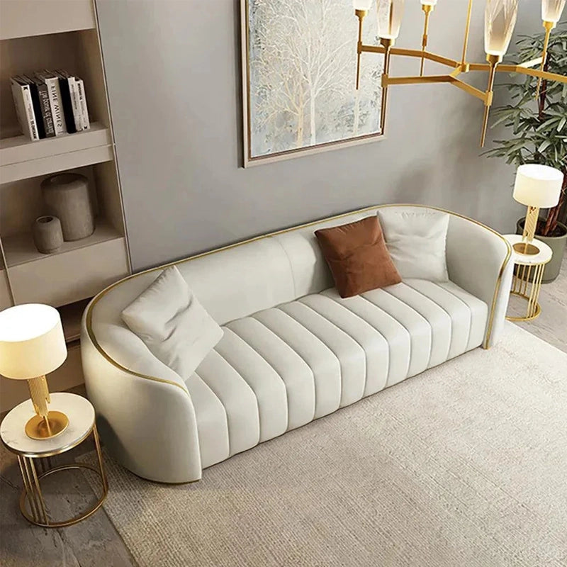 Designed with a sculptural profile, it features soft-touch fabric, gold metal legs, and smooth rounded edges.